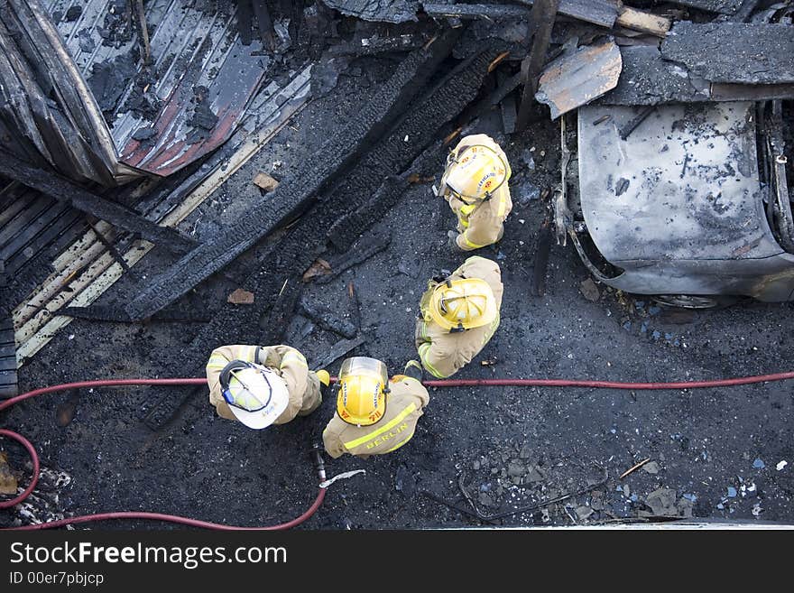 A photo of firemen conversing at a recent fire site. A photo of firemen conversing at a recent fire site