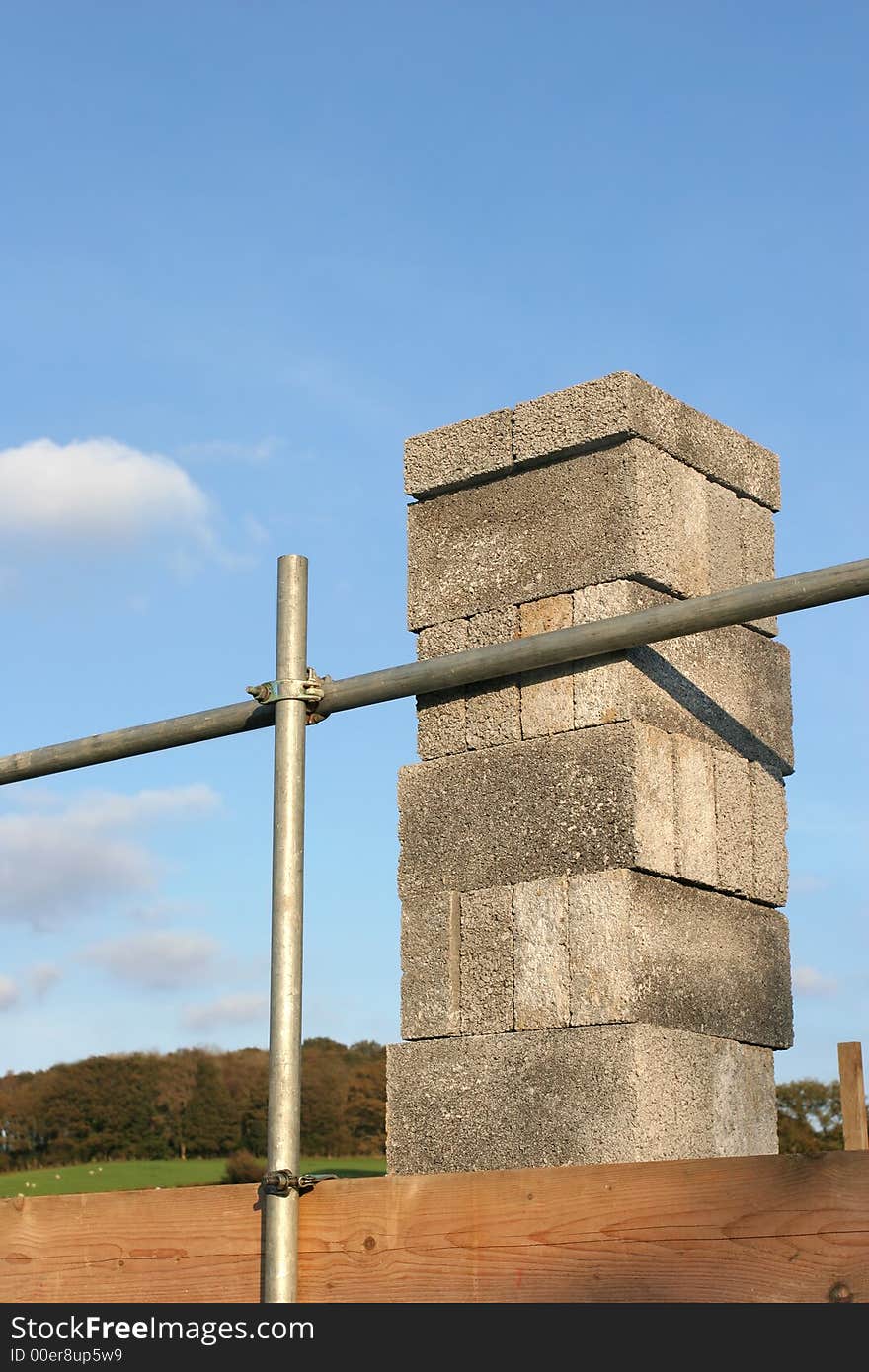 Concrete blocks stacked on scaffolding against a blue sky.