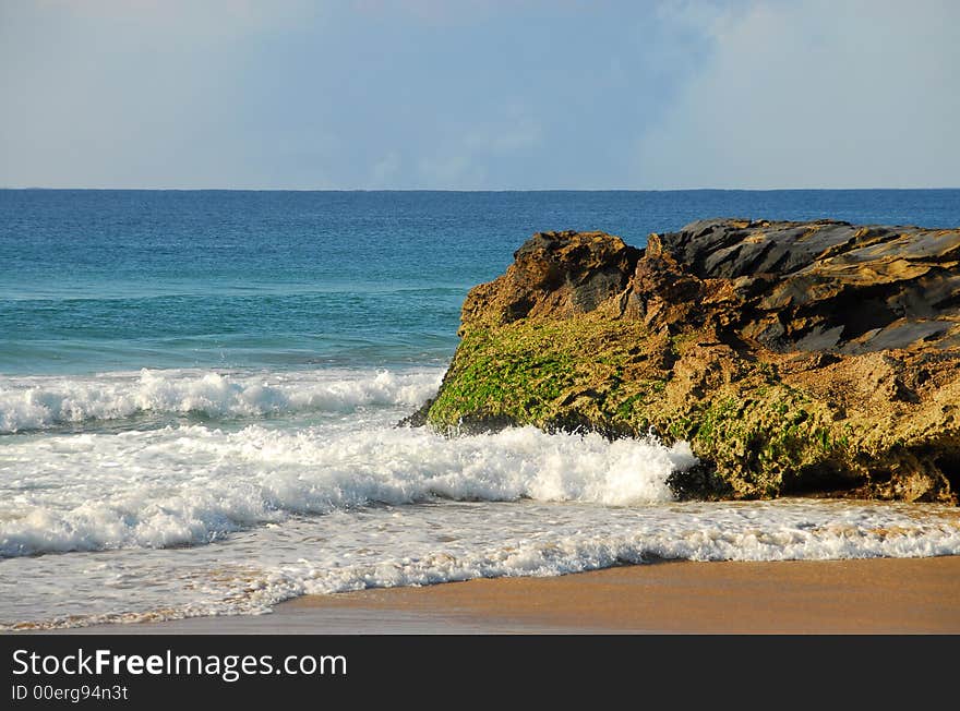 Waves rolling into the shore around a large rock on a beach in Australia. Waves rolling into the shore around a large rock on a beach in Australia