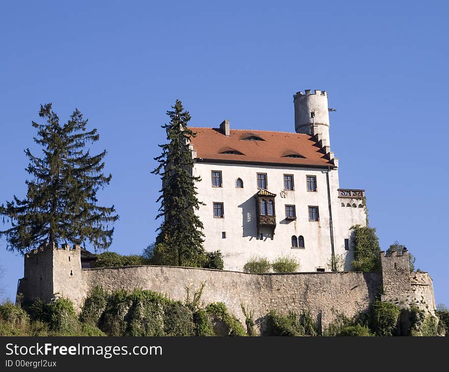 White castle with tower and main house in front of blue sky