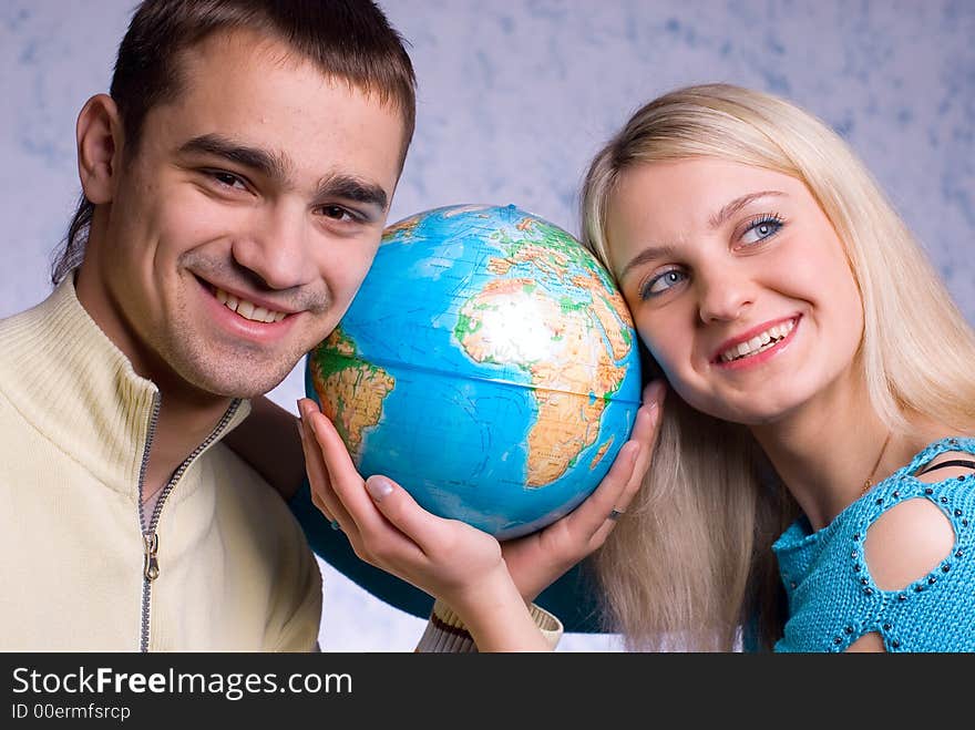 The guy and the girl hold the globe on a blue background