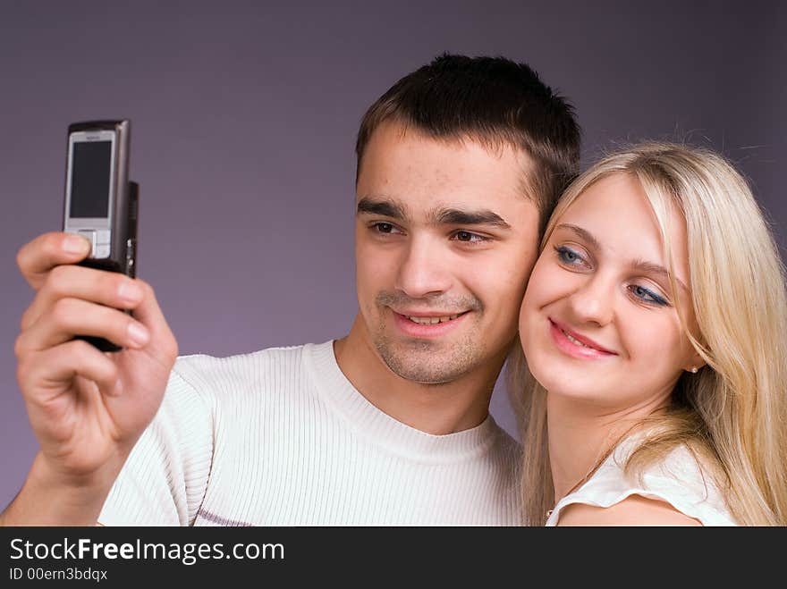 The guy and the girl with mobile phone on a grey background