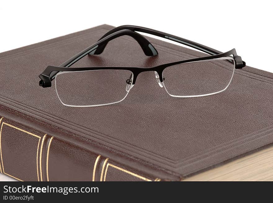 Eyeglasses and a brown book on a white background. Eyeglasses and a brown book on a white background.