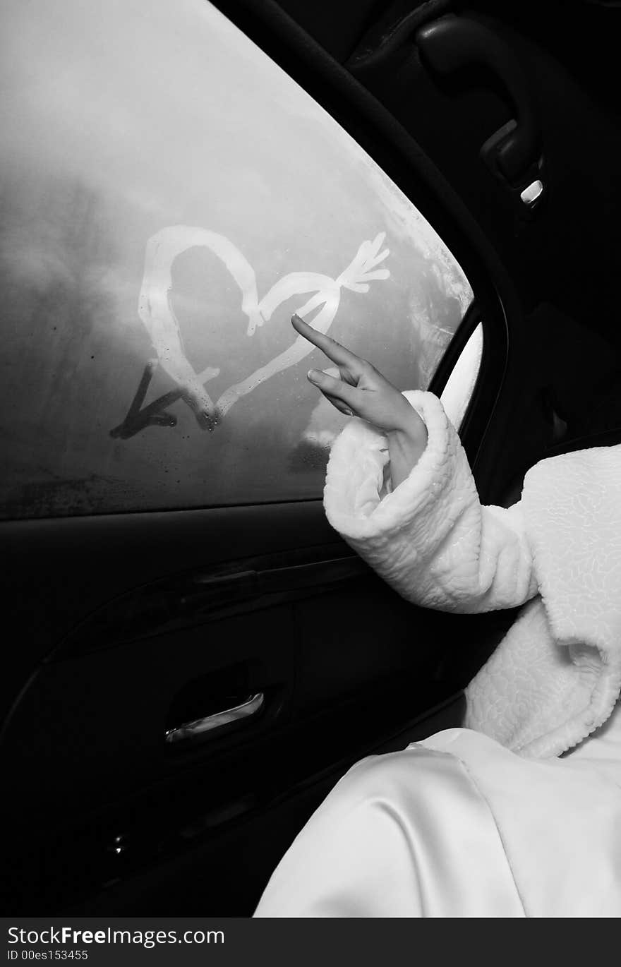 The bride draws heart at a window of the automobile