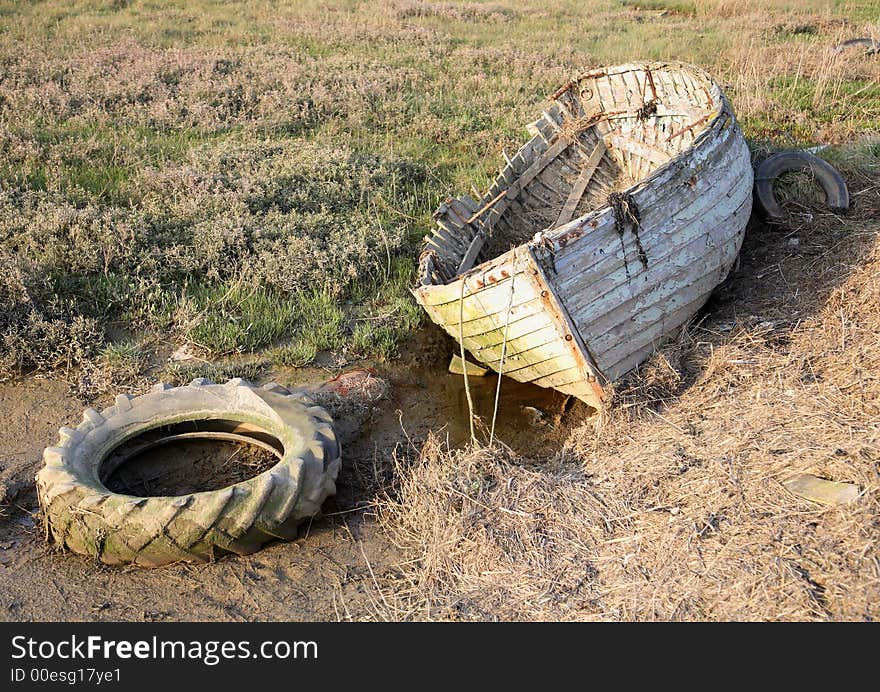 Rotten old rowing boat with tyre. Rotten old rowing boat with tyre