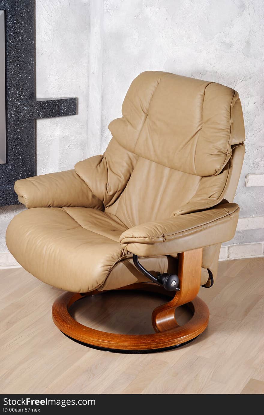 Modern leather arm chair with wooden stand near wall. Modern leather arm chair with wooden stand near wall