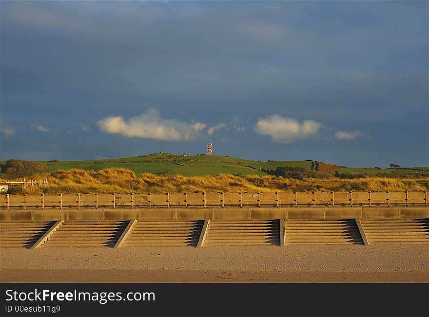 Promenade viewed from the beach with dunes and distant hillside. Promenade viewed from the beach with dunes and distant hillside.