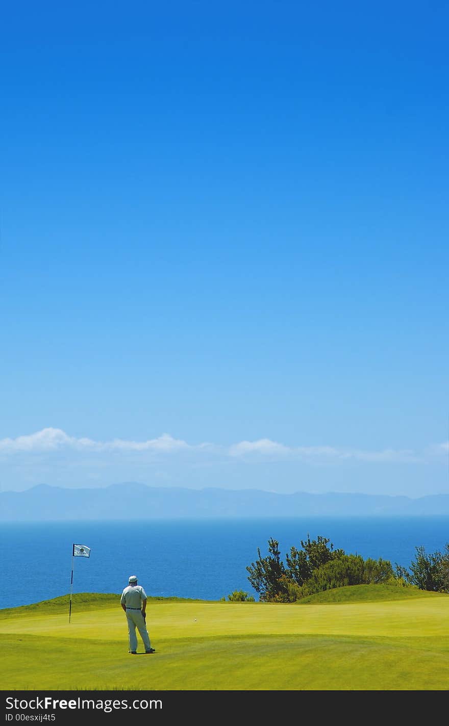 A man golfing with catalina island in the background