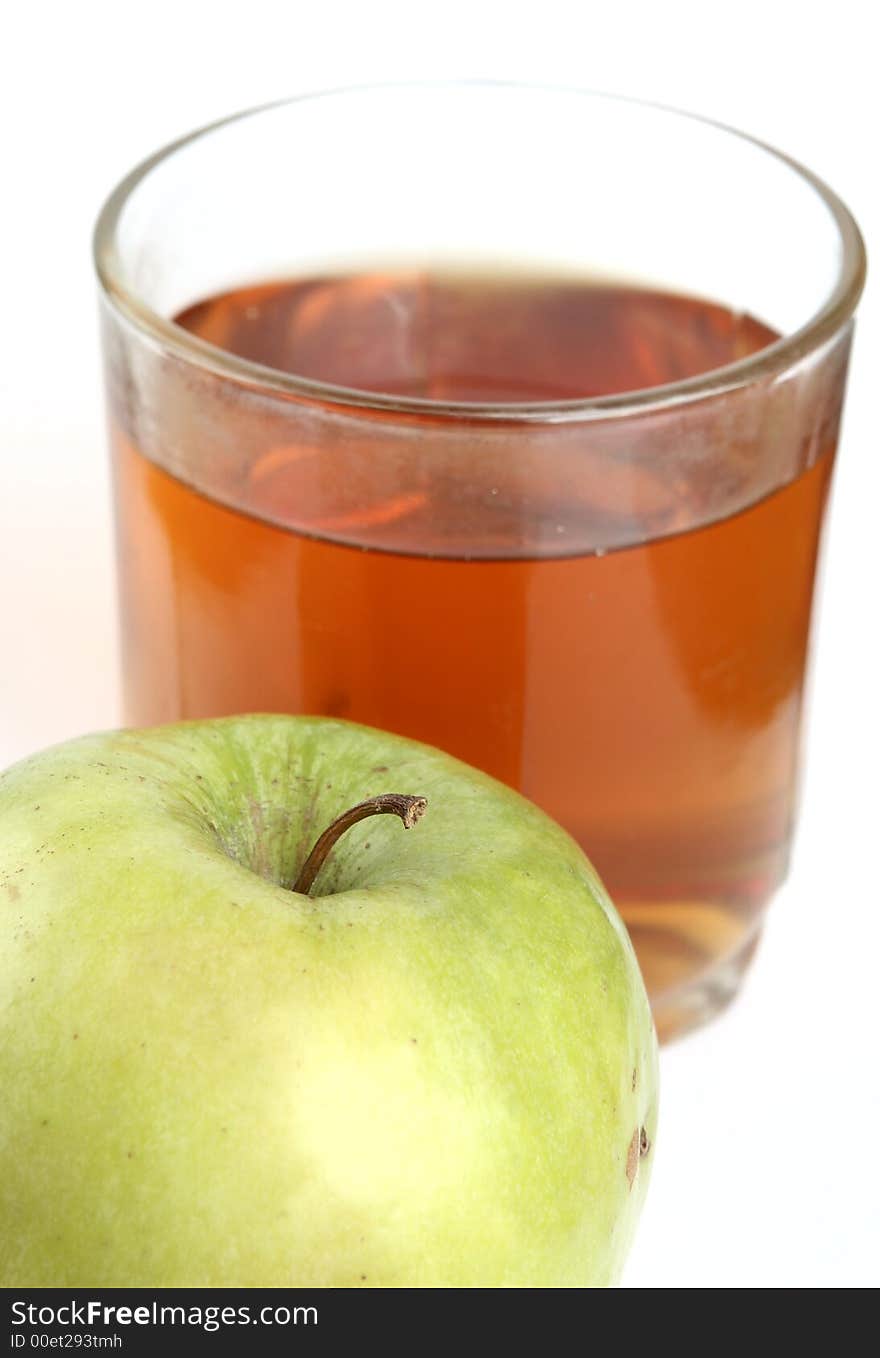 Green apple and glass of juice on a white background