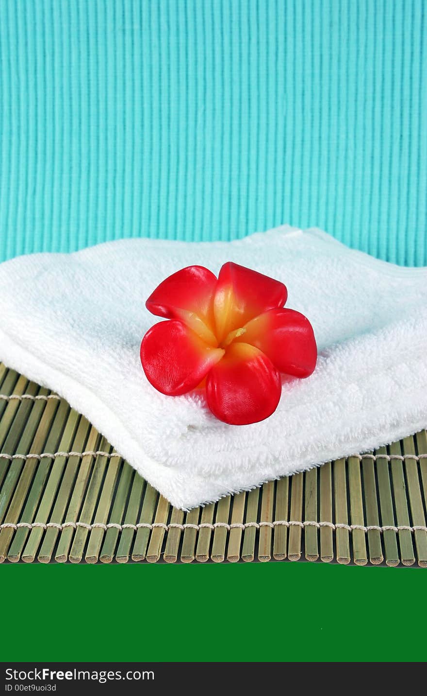 Fragapani flower candle on a white towel - spa products