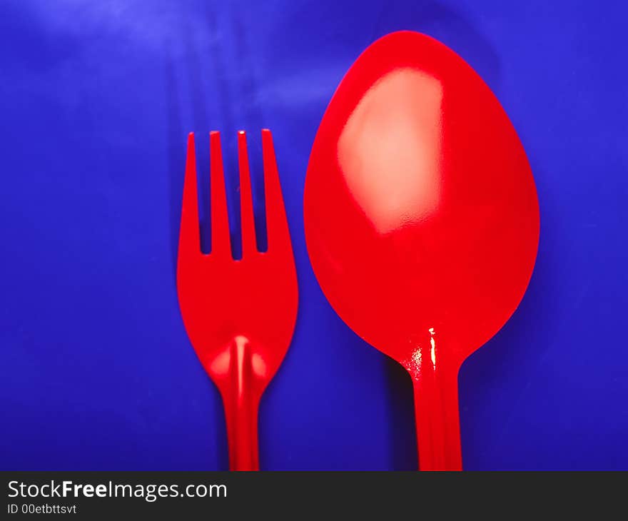 Brightly red spoon and plug on  dark blue background, close up. Brightly red spoon and plug on  dark blue background, close up