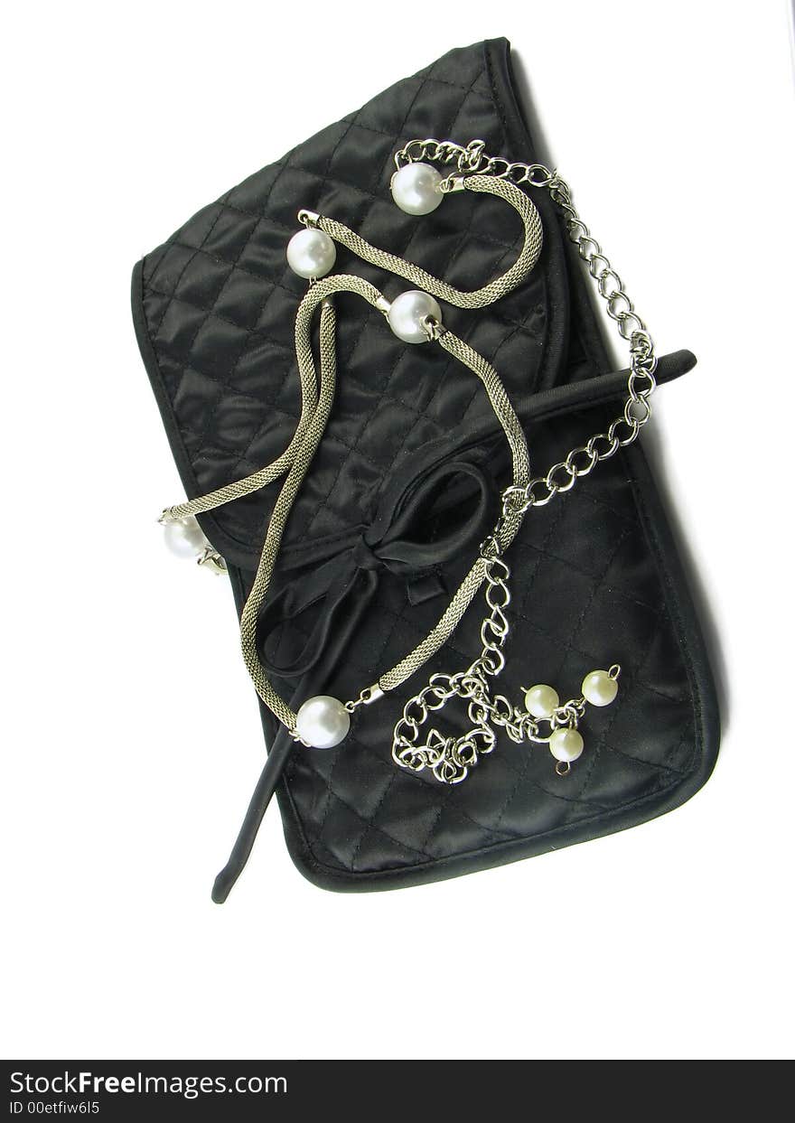 Silver beads with the pearls lie on the small, black bag. It is isolated against the white background. Silver beads with the pearls lie on the small, black bag. It is isolated against the white background.