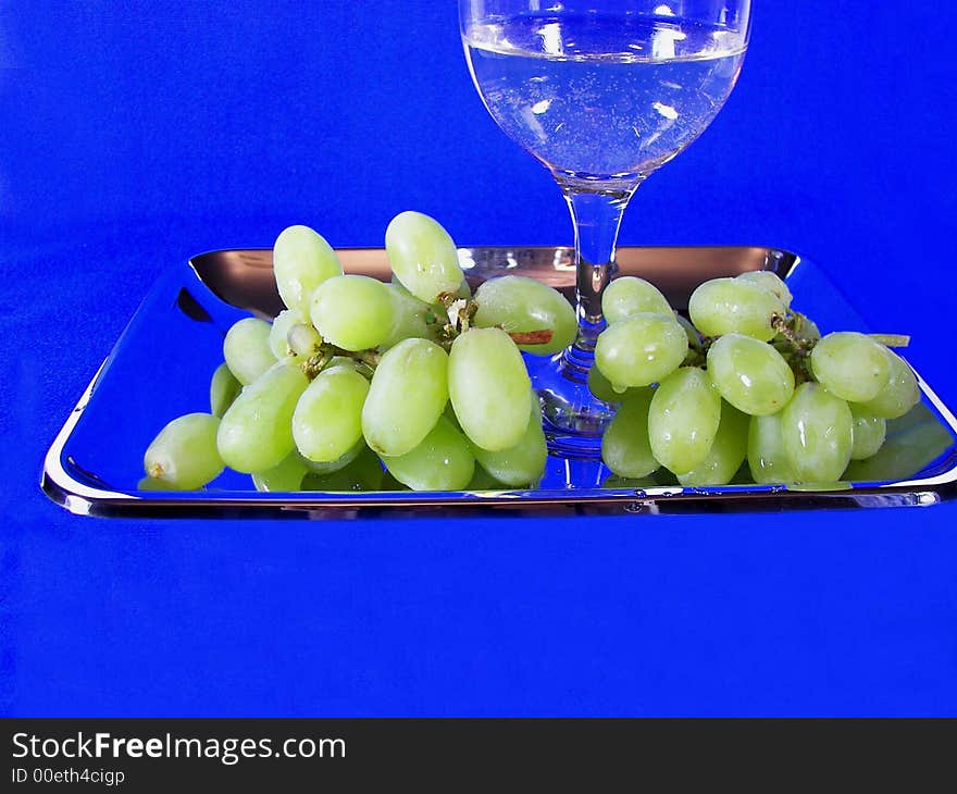 Cluster of green grapes and glass of wine in silver tray. Cluster of green grapes and glass of wine in silver tray