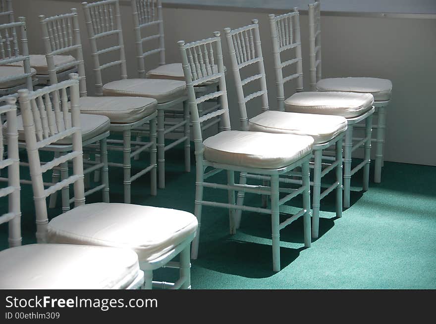 Rows of white chair with sun shining on front row. Rows of white chair with sun shining on front row