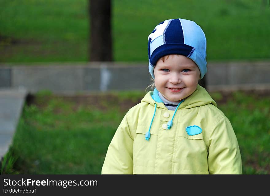 The child in autumn clothes on a background of green park. The child in autumn clothes on a background of green park