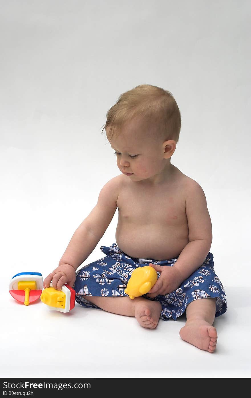 Image of an adorable baby wearing shorts, playing with toy boats. Image of an adorable baby wearing shorts, playing with toy boats