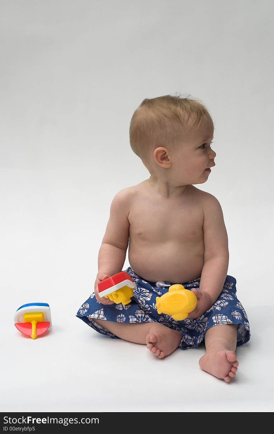 Image of an adorable baby wearing shorts, playing with toy boats. Image of an adorable baby wearing shorts, playing with toy boats