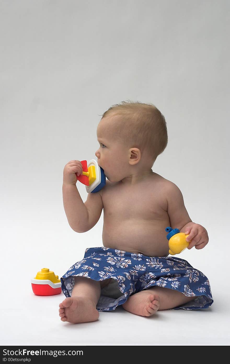 Image of an adorable baby wearing shorts, playing with toy boats. Image of an adorable baby wearing shorts, playing with toy boats