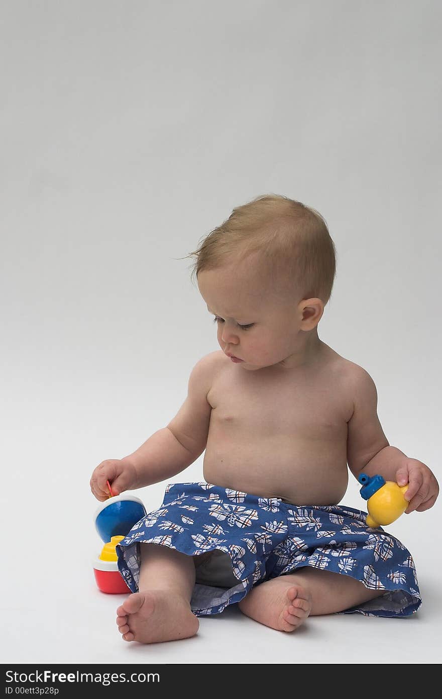 Image of an adorable baby wearing shorts, playing with toy boats. Image of an adorable baby wearing shorts, playing with toy boats