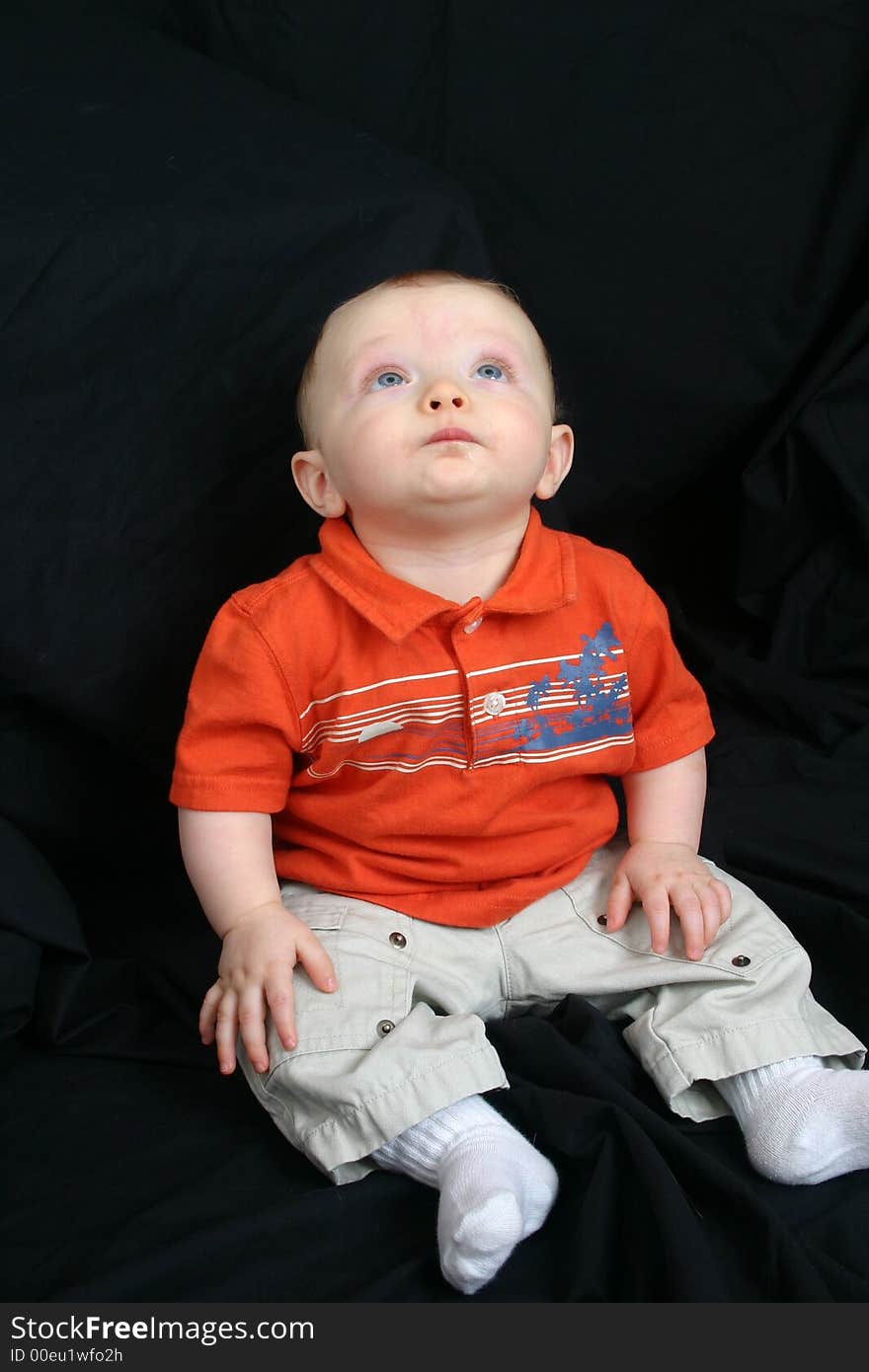 Cute little boy sitting in a black background