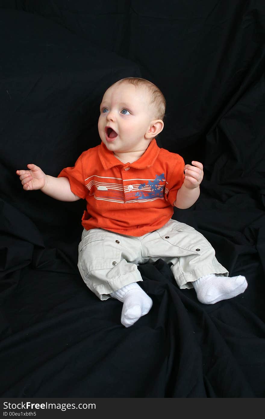 Cute little boy sitting in a black background