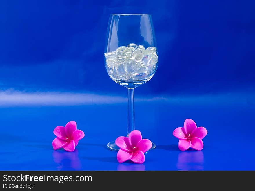 Wine glass with sparkling stones on a blue background. Wine glass with sparkling stones on a blue background