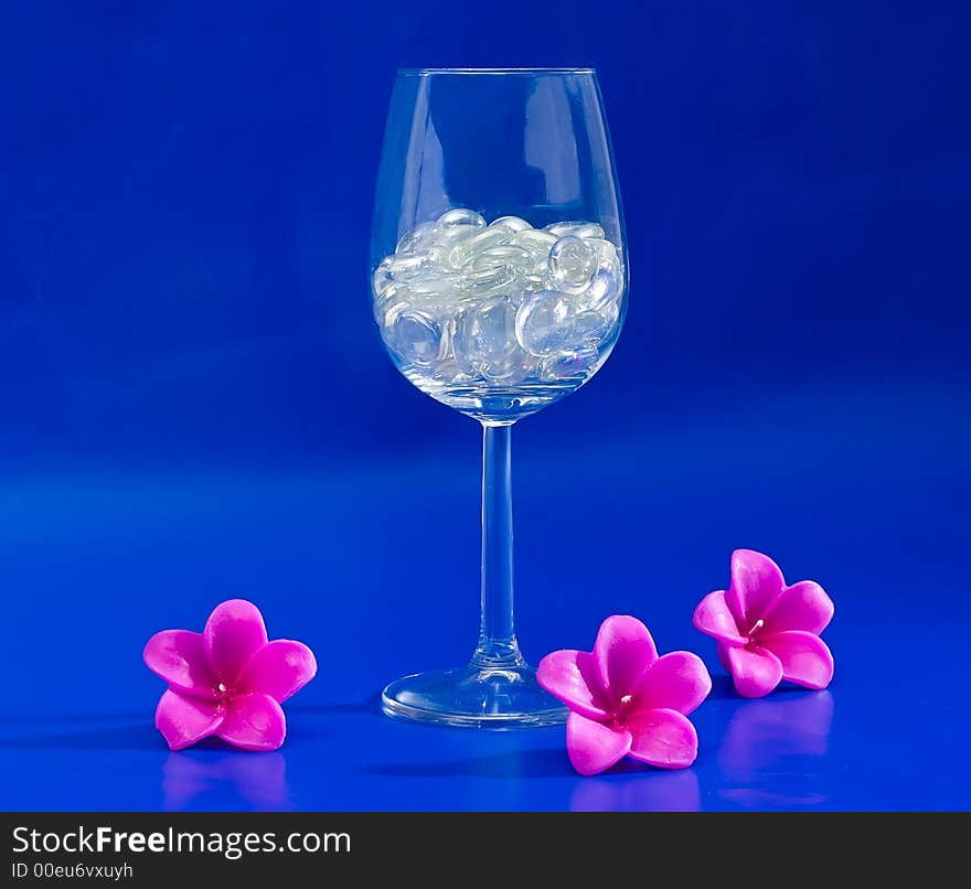 Wine glass with sparkling stones on a blue background. Wine glass with sparkling stones on a blue background