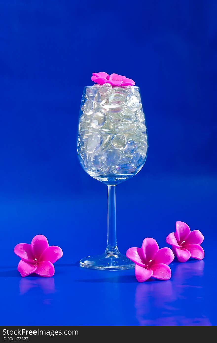 Wine glass with sparkling stones on a blue background. Wine glass with sparkling stones on a blue background