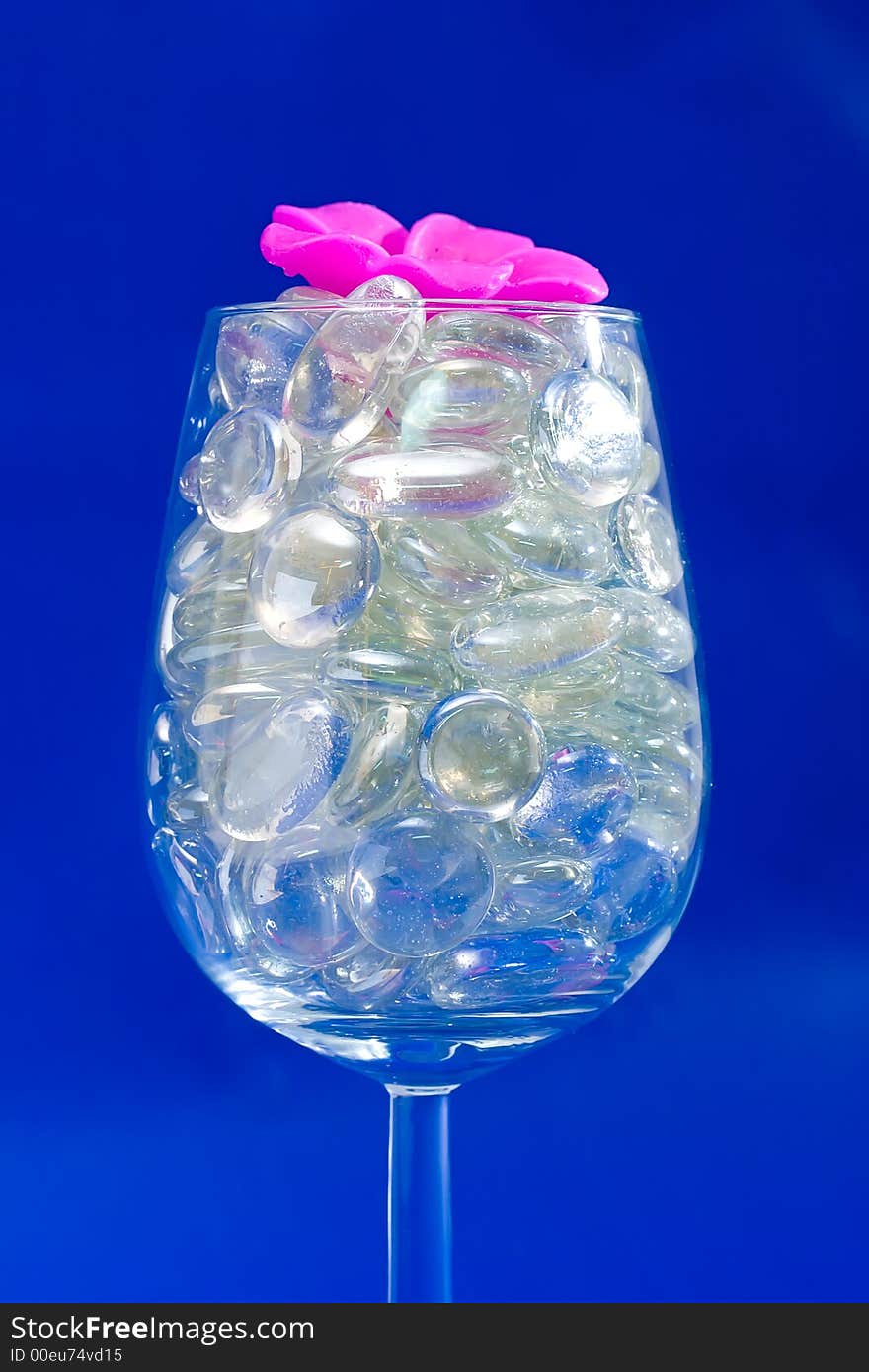 Wine glass with sparkling stones on a blue background. Wine glass with sparkling stones on a blue background