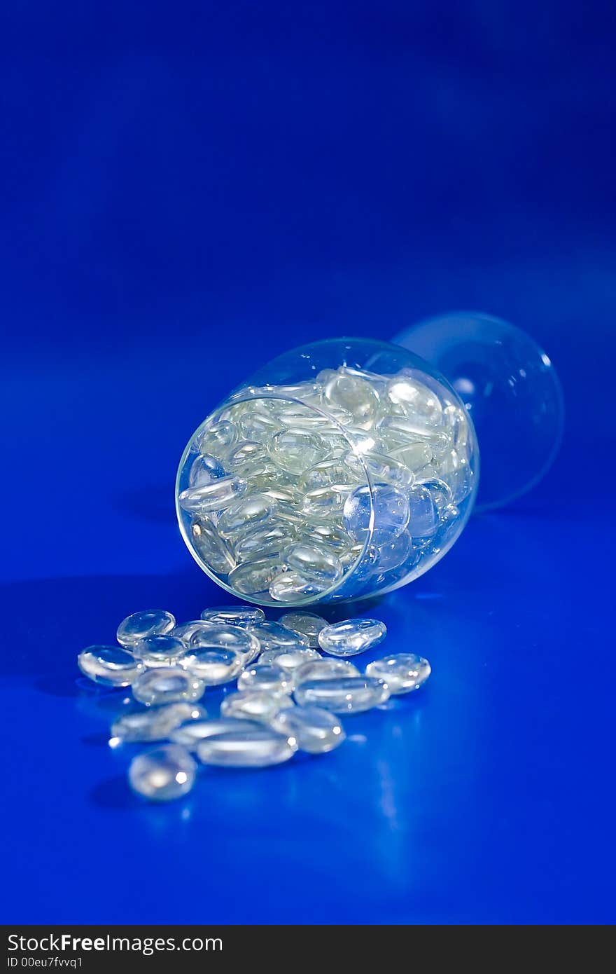 Wine glass with sparkling stones on a blue background. Wine glass with sparkling stones on a blue background