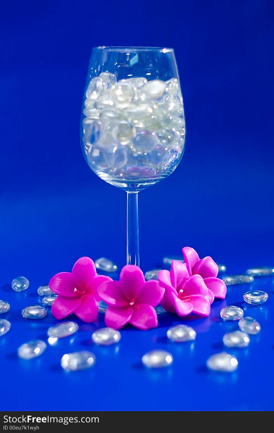 Wine glass with sparkling stones on a blue background. Wine glass with sparkling stones on a blue background