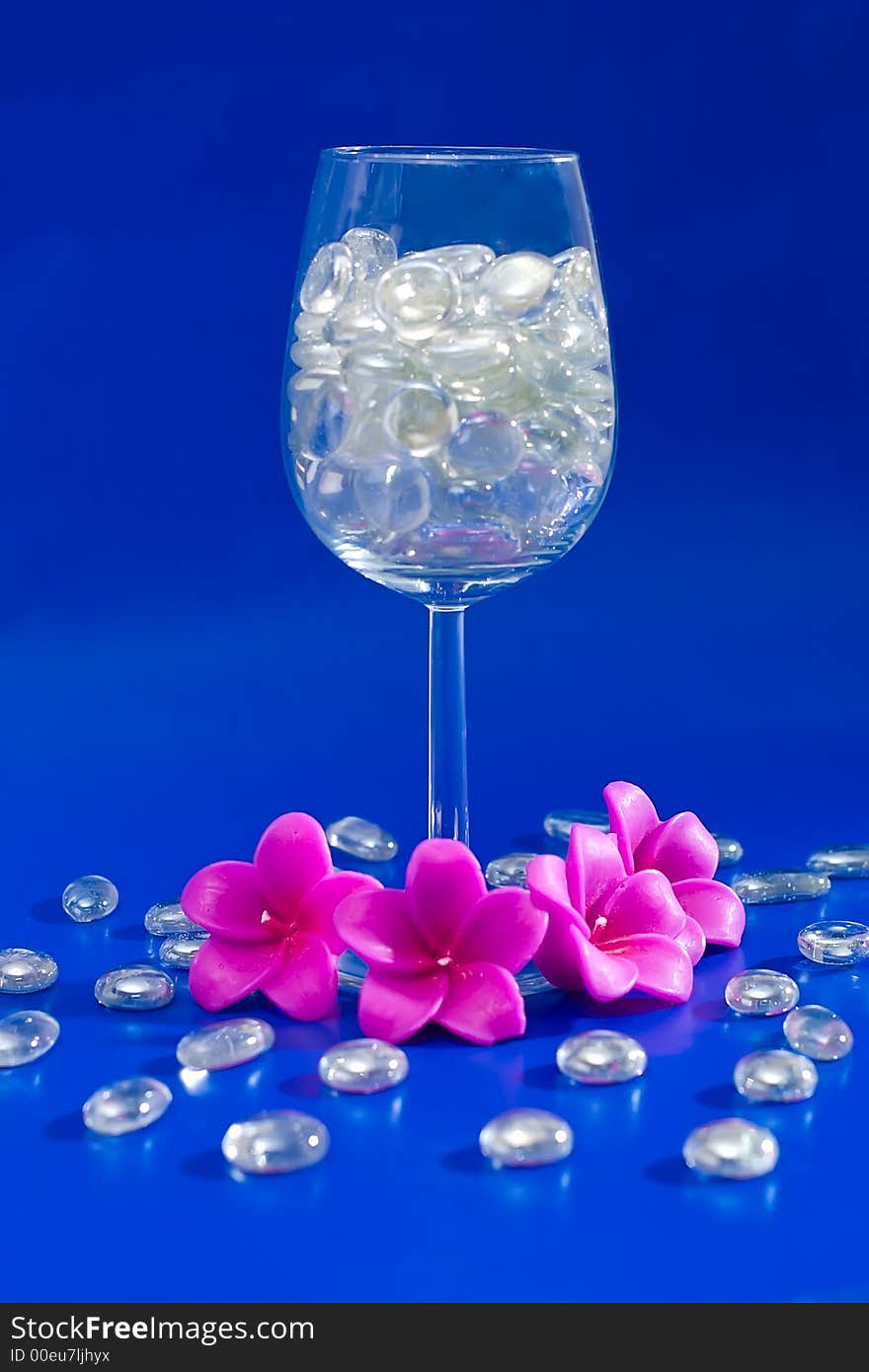 Wine glass with sparkling stones on a blue background. Wine glass with sparkling stones on a blue background