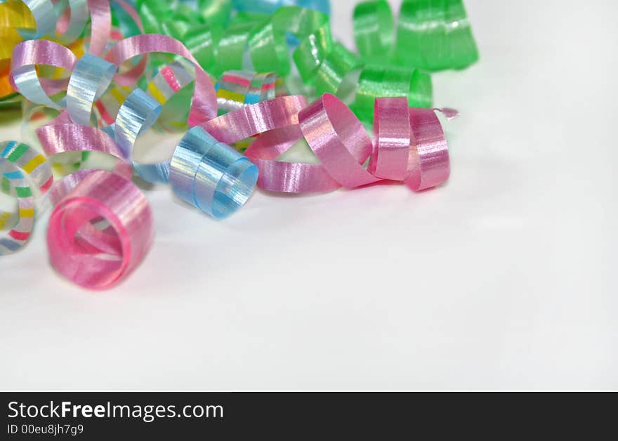 Curls of pastel colored ribbons in the upper left corner on white. Curls of pastel colored ribbons in the upper left corner on white.