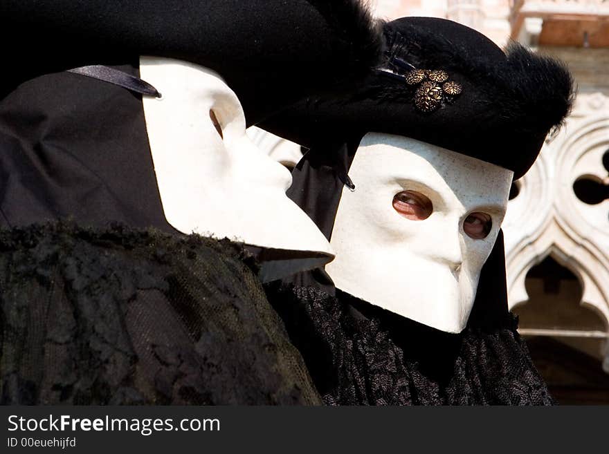 Two Venetians in black costumes and white masks