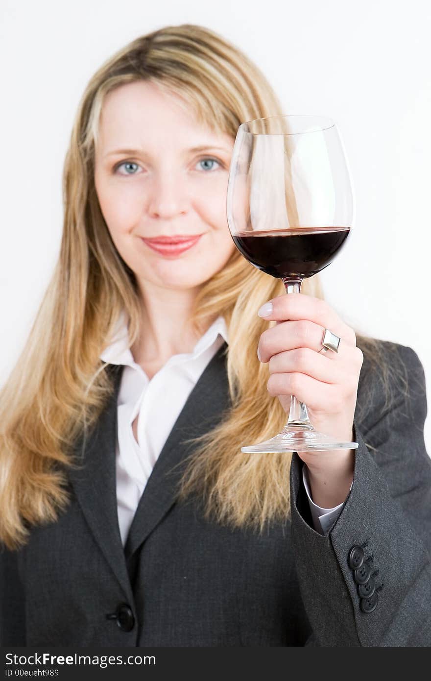 A young business woman holding a glass of red wine. Focus on the wine glass. A young business woman holding a glass of red wine. Focus on the wine glass