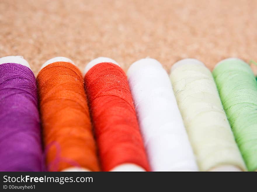 Six rolls of cotton on a cork background