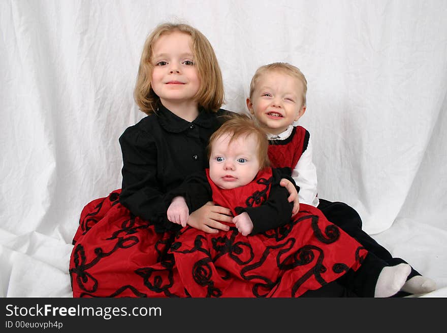 Three kids sitting together on a white background