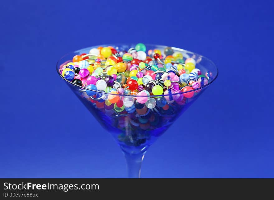 A martini glass full of navel rings. On Saturated Blue Background. A martini glass full of navel rings. On Saturated Blue Background