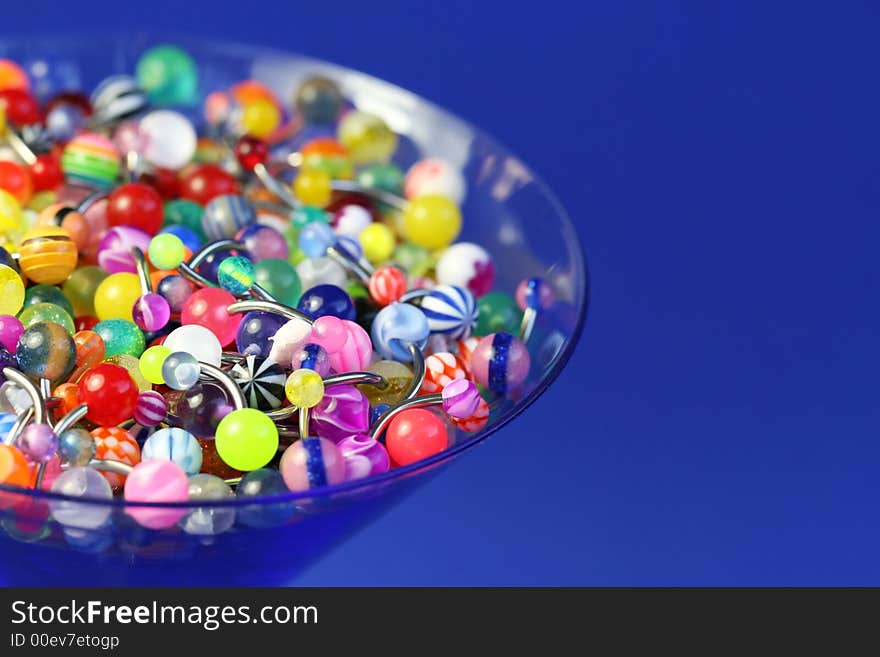 A martini glass full of navel rings. On Saturated Blue Background. A martini glass full of navel rings. On Saturated Blue Background