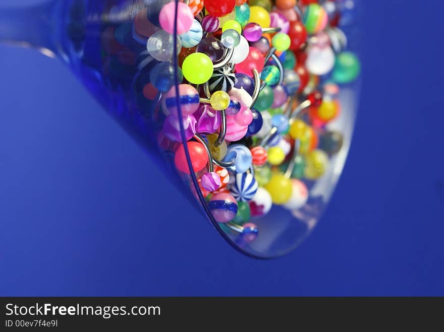 A martini glass full of navel rings. On Saturated Blue Background. A martini glass full of navel rings. On Saturated Blue Background