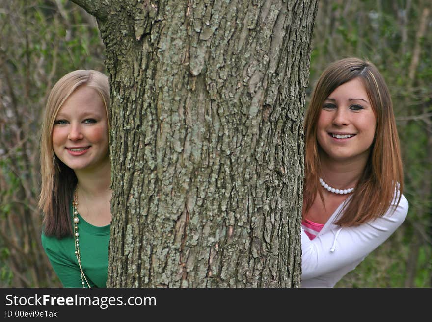 Girls Peeking Around A Tree