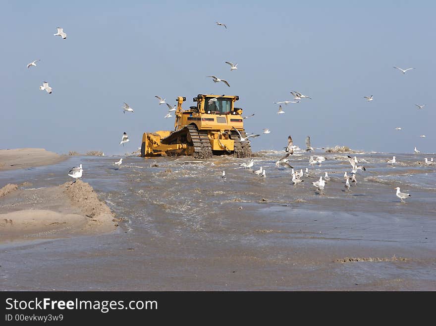 The bulldozer has to straighten the sand after they have spouted up the sand