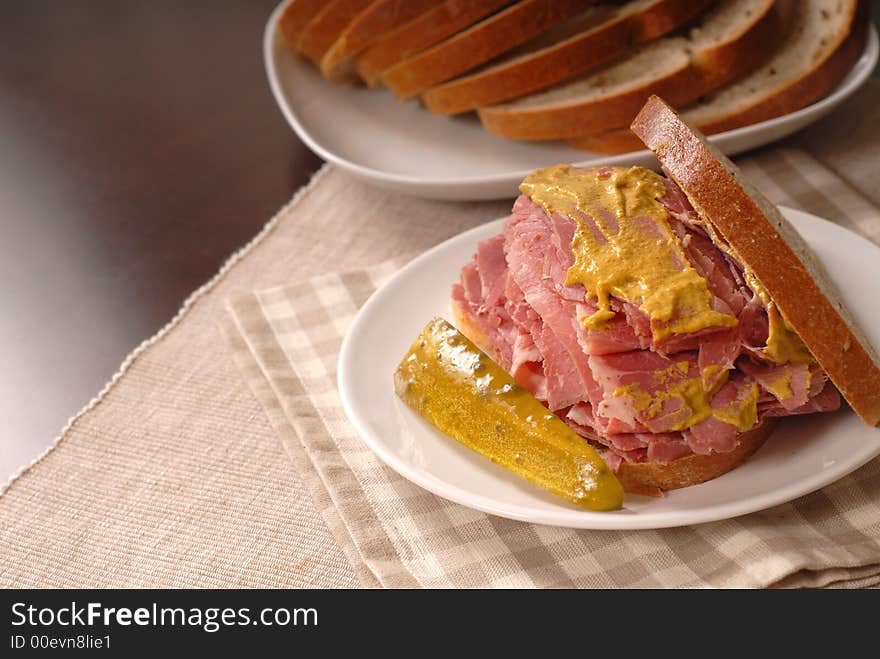 A corned beef sandwich with mustard on rye bread