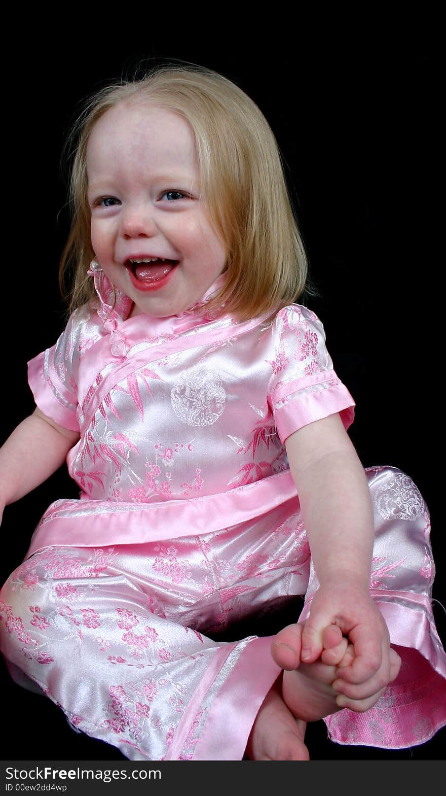 Little girl laughing sitting on a black background