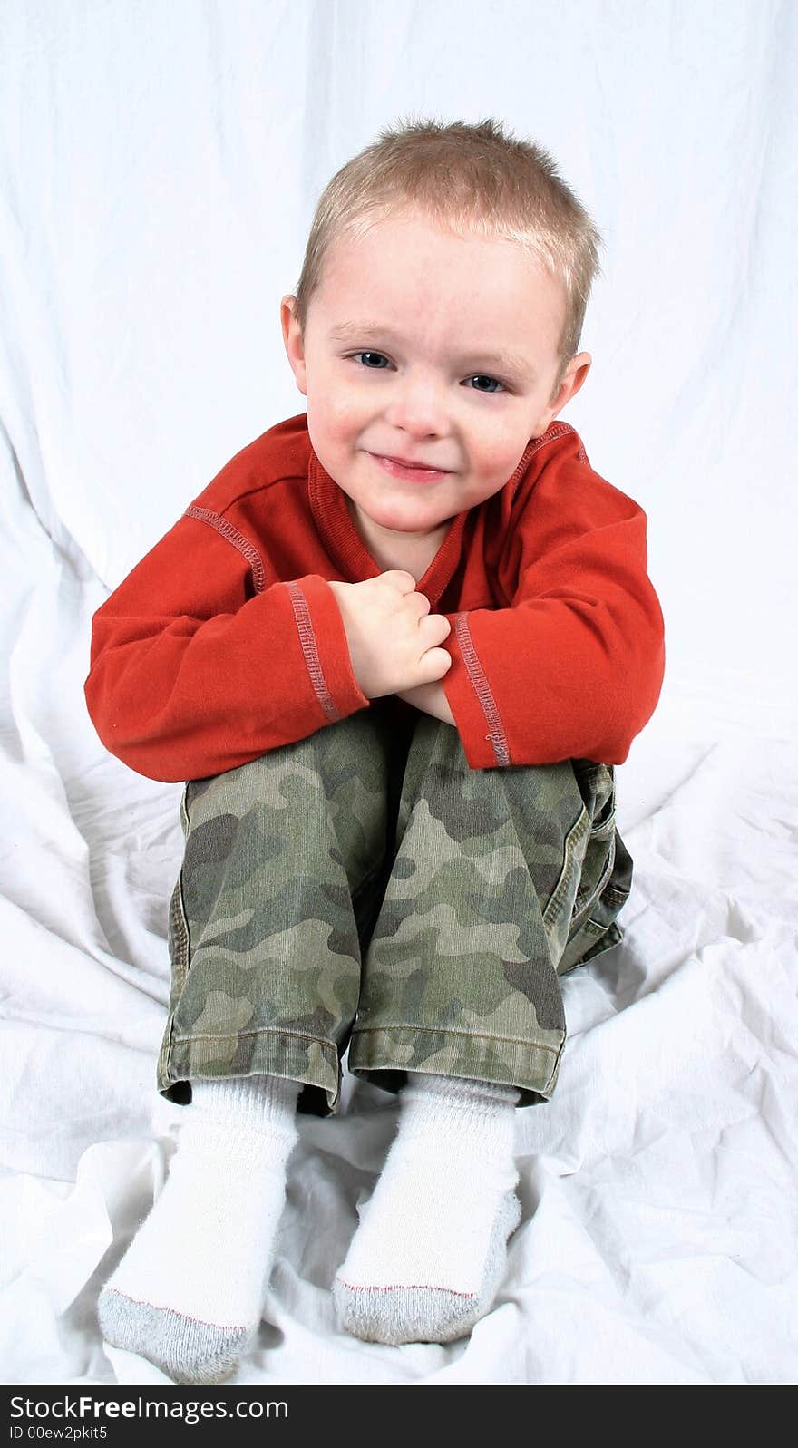 Cute little boy sitting on a white background