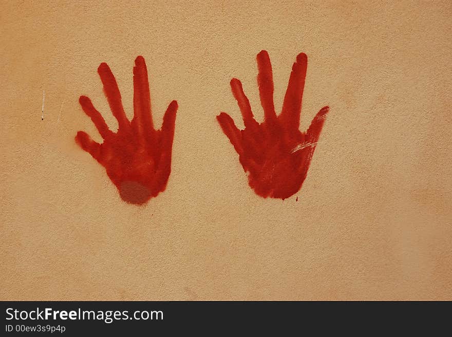 Red hands painted on a wall with artistic effect. Red hands painted on a wall with artistic effect