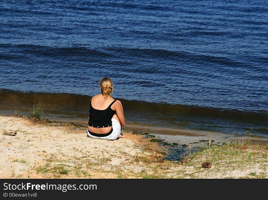 Girl sitting alone staring into the water. Girl sitting alone staring into the water