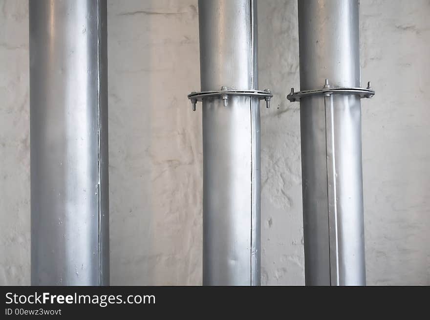 Gray industrial pipes over white brick wall