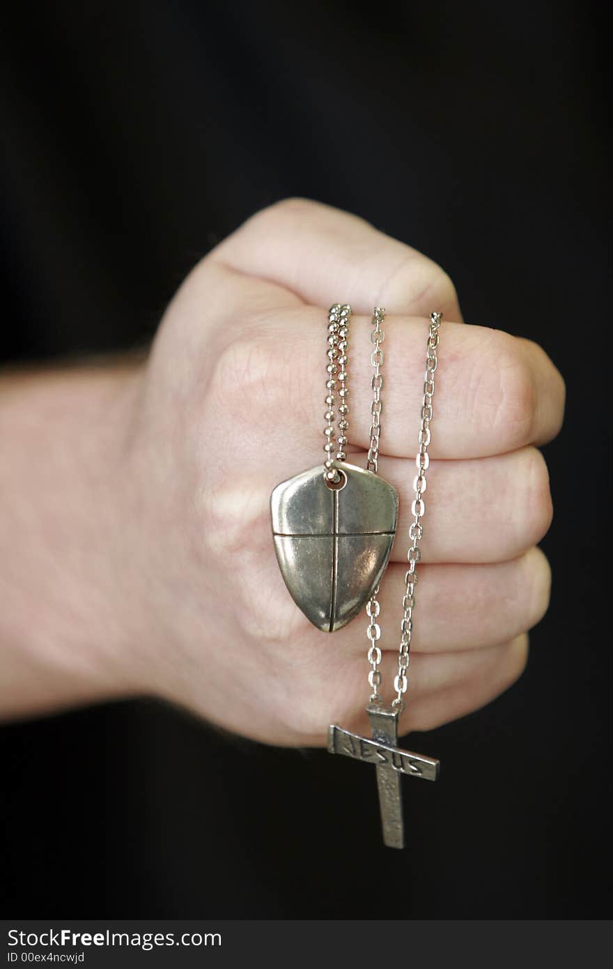 White male making a fist with necklaces with crosses on a black background