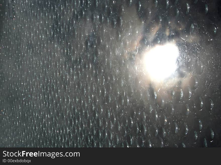 Water drops on a window with the sun reflecting in the glass. Water drops on a window with the sun reflecting in the glass.